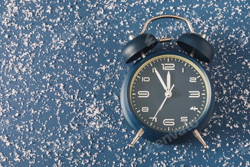 Preview: Alarm clock over a cold blue background with scattered snow
