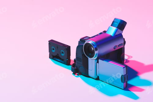 Preview: close up view of video cassette and digital video camera on pink background
