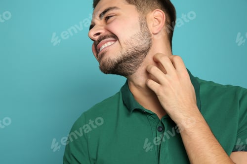 Preview: Young man scratching neck on color background. Annoying itch