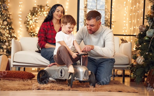 Preview: Kid is riding on the little bike. Happy family celebrating new year together at home