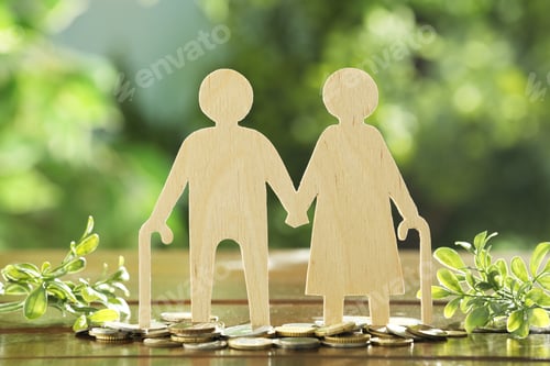 Preview: Pension savings. Figure of senior couple, coins and green twigs on wooden table outdoors