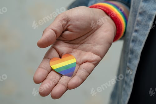 Preview: Asian lady holding rainbow color flag heart, symbol of LGBT pride month celebrate annual.