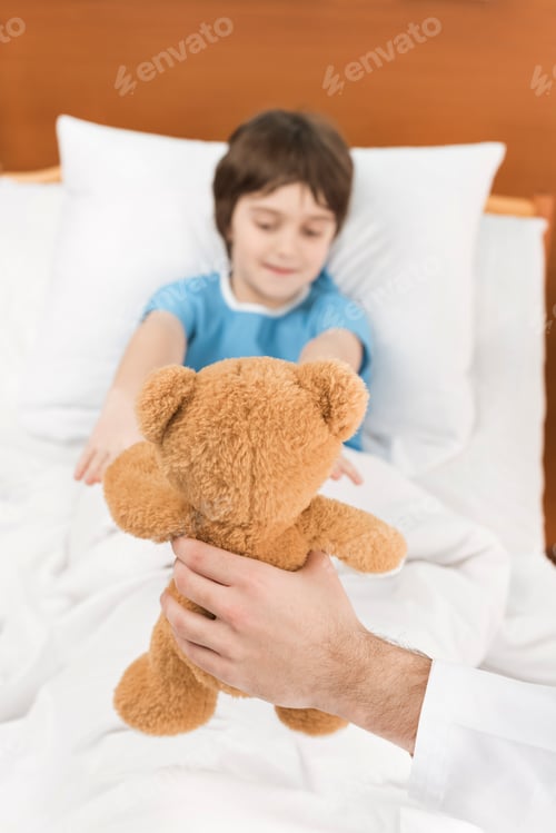 Preview: doctor showing child patient in bed teddy bear
