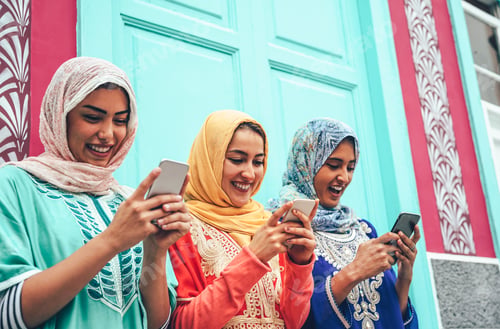 Preview: Young Muslim friends using mobile smartphones in the college
