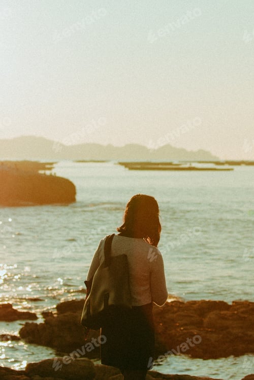 Preview: Young woman in front of the ocean during a super sunny day with vintage styling