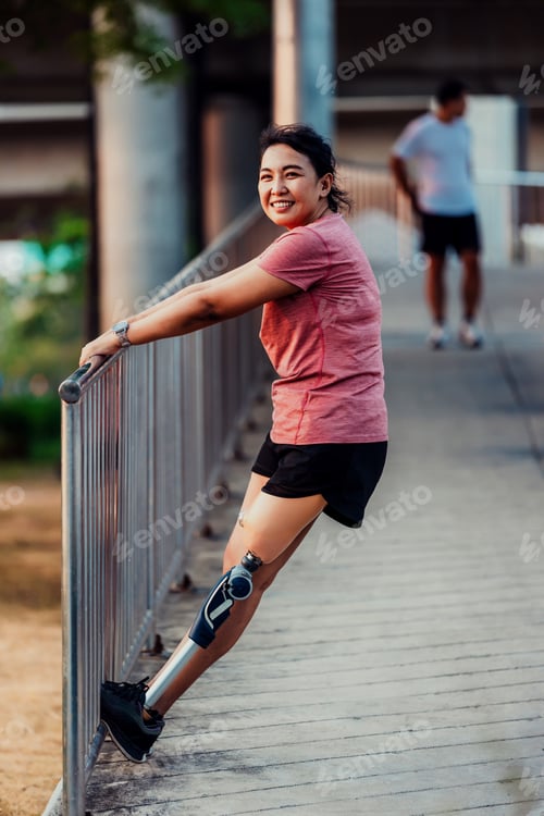 Preview: Athlete with prosthetic leg doing warm up exercise on park.