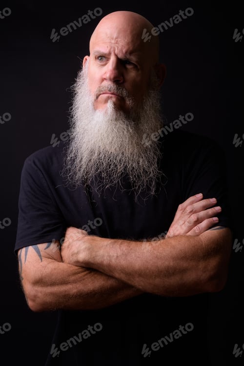 Preview: Mature bald bearded man against black background