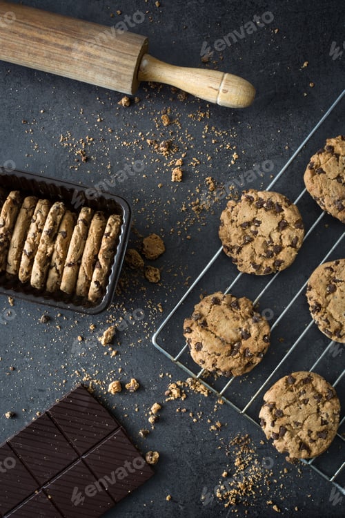 Preview: Chocolate chip cookies cooling on a wire rack with crumbs and rolling pin
