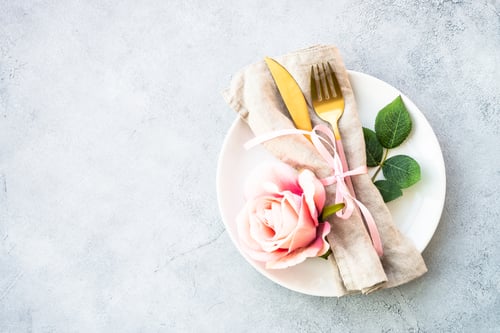 Preview: Table setting with white plate, cutlery and flowers.