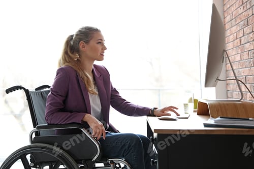 Preview: Woman in wheelchair working with computer at table indoors