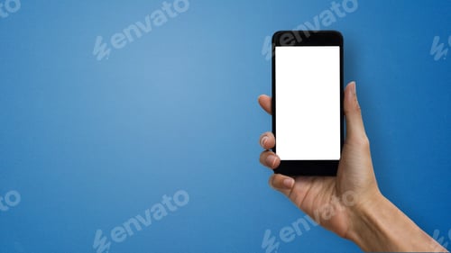 Preview: A man hand holding smartphone with white screen and space at left hand on blue background.