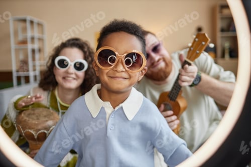 Preview: Portrait of Smiling Adopted Black Boy in Sunglasses Recording Video with Parents Indoors