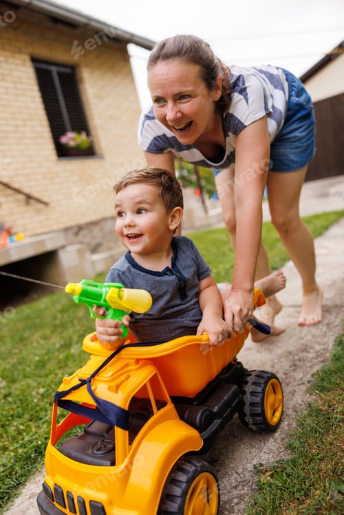 Preview: Mother having fun pushing child in toy truck