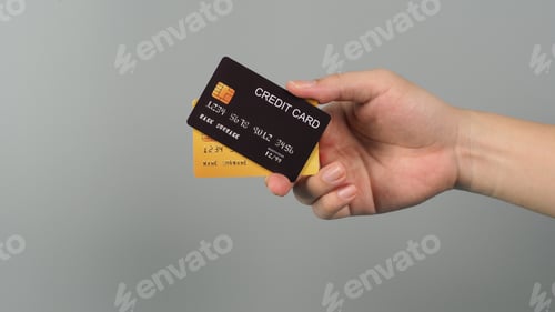 Preview: Hand is holding two credit card in black and gold color isolated on grey background.