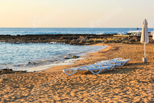 Preview: Tropical beach view with white empty chairs. Social distancing, cancellation of vacation.
