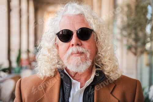 Preview: Confident and introspective senior man with curly hair and sunglasses striking a serious pose