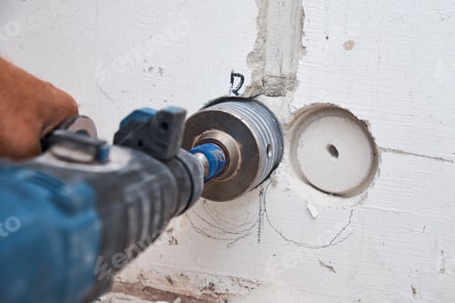 Preview: Builder with hummer drill perforator drills hole in a wall