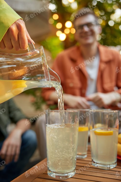 Visualização: Friends at table with fresh lemonade having fun at outdoor picnic