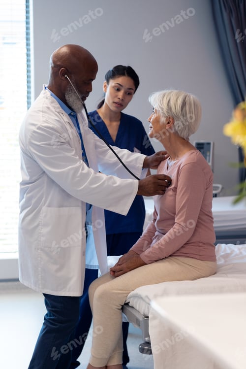 Preview: Vertical of diverse senior male doctor using stethoscope examining senior female patient, copy space