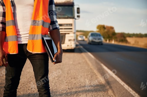 Preview: Modern technology concept. With tablet. Black man is standing on the road with truck on it