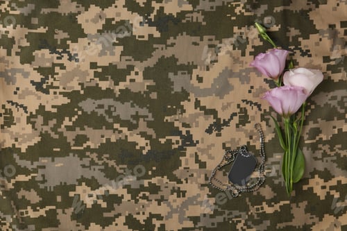 Preview: Fresh flowers and ID tag on camouflage background, flat lay with space for text. Armed Forces Day