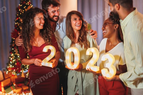 Amigos segurando números iluminativos 2023 na contagem regressiva da meia-noite da véspera de Ano Novo