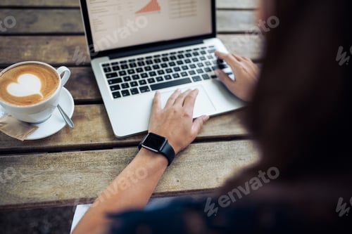 Preview: Female with smartwatch using laptop at cafe