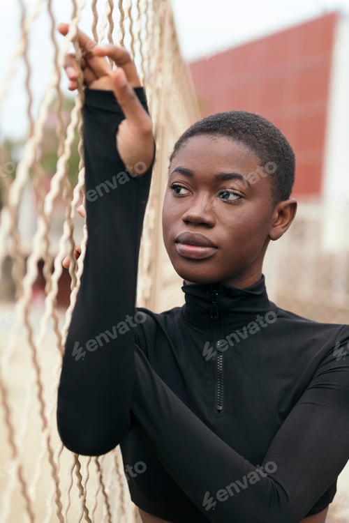 Preview: melancholic black woman near grid fence in town