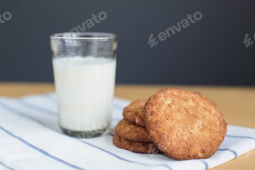 Preview: round brown wholegrain flour cookies and milk glass on striped white napkin on wooden table