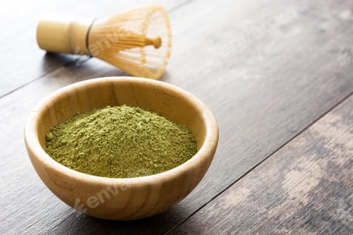 Preview: Matcha green tea powder in wooden bowl with bamboo whisk on wooden table