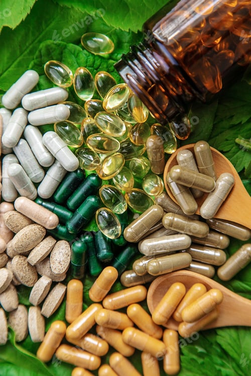 Preview: Capsules herb supplements on green leaves background. Selective focus.
