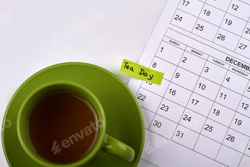 Preview: Top view cup of tea and month calendar on white desk.