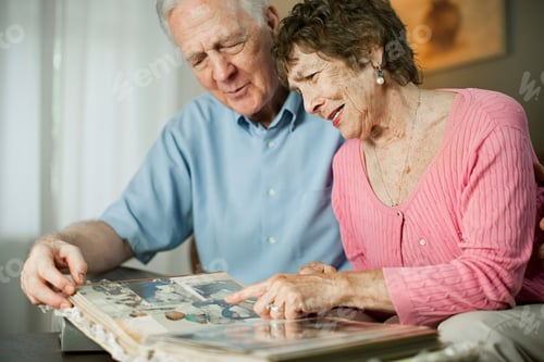 Preview: Senior couple enjoying memories with a photo album.