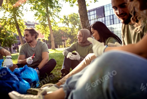 Preview: Multiethnic group of volunteers resting after cleaning city park.