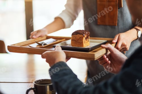 Preview: A waitress holding and serving a piece of choux cream to customer in cafe