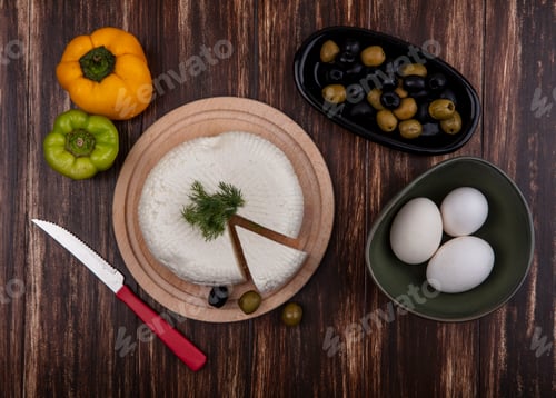 Preview: top view chicken eggs in a bowl with feta cheese on a stand with bell pepper and bolivi on a wooden