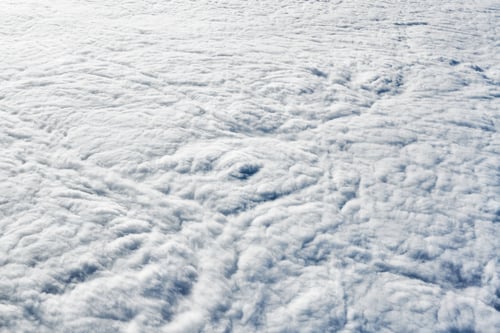 Preview: Breathtaking over clouds view from aircraft window, thick white blue clouds looks like soft foam