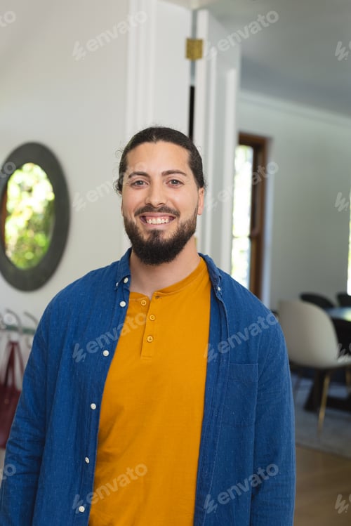 Preview: Happy caucasian man with beard standing and smiling in sunny house