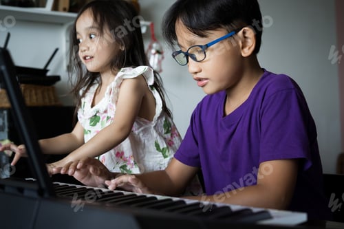 Preview: Brother and little sister are playing keyboard instrument together.