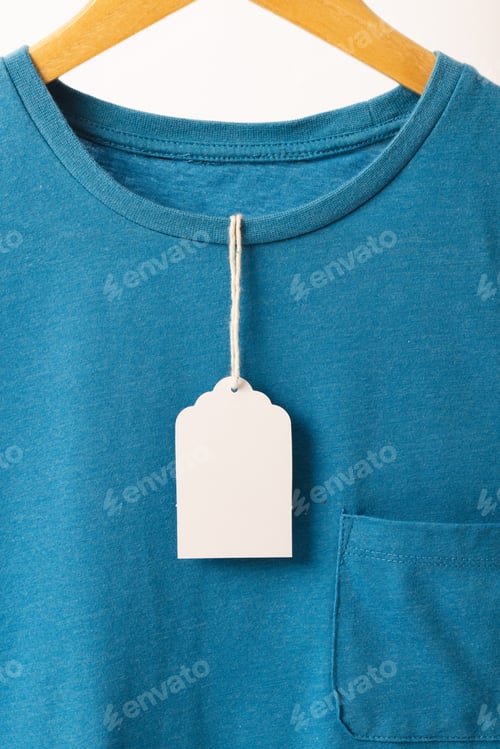Preview: Blue t shirt with tag on hanger with copy space on white background
