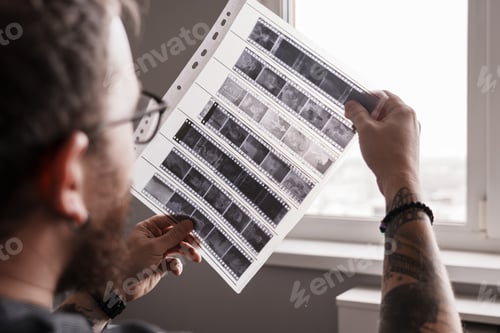 Preview: Photographer examining film negatives by window light