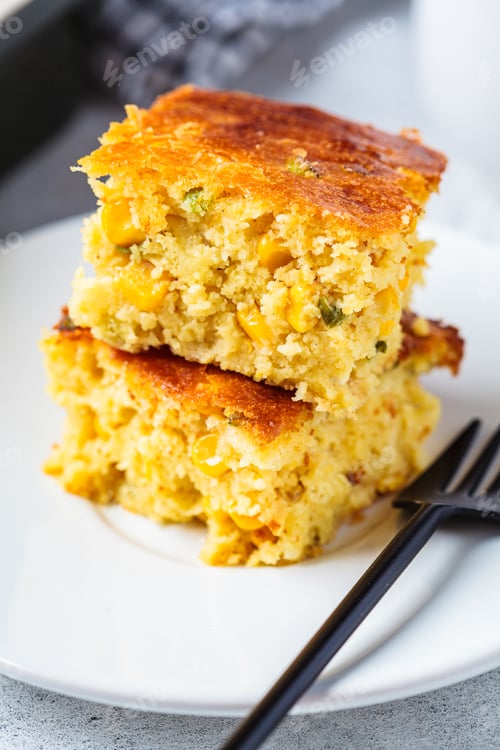 Preview: Portion of Christmas cheddar cornbread on white plate. Festive recipe food concept.