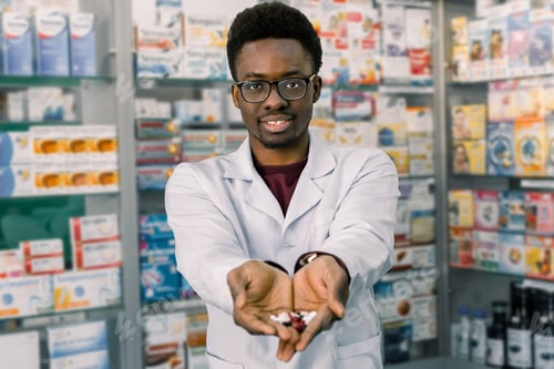 Preview: African-american pharmacist man holding tablets pills in the hands. Man's hands holding a