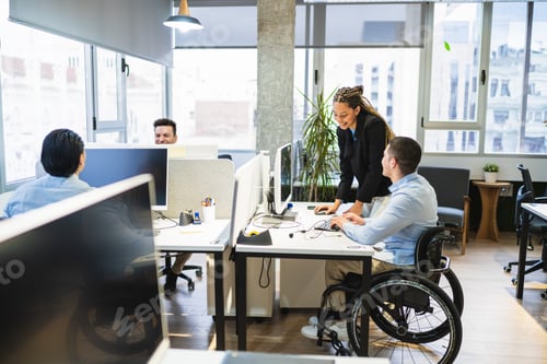 Preview: Professionals one using wheelchair collaborating in coworking space embracing diversity and teamwork