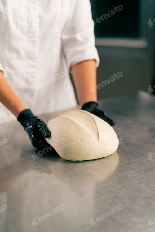 Preview: baker's hands in the kitchen forming dough into a perfect bread shape for sale in a bakery