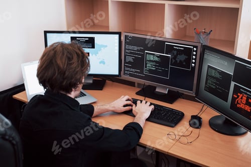 Preview: man uses a laptop computer with many monitors