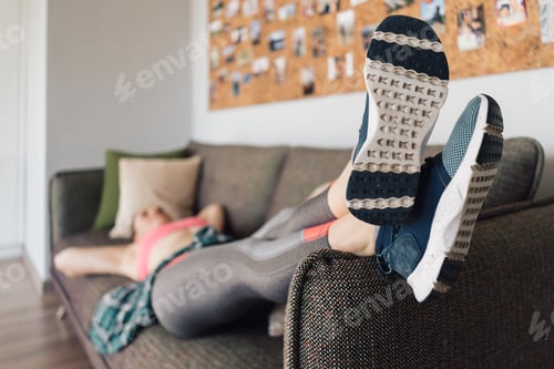 Preview: Sporty woman resting relaxed on the sofa