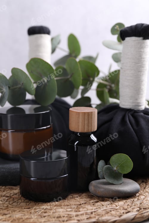 Preview: Spa composition with cosmetic products, herbal massage bags, stones and eucalyptus branches on table