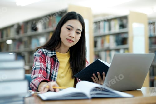 Preview: Young university student using laptop for online learning, searching and learning at library.
