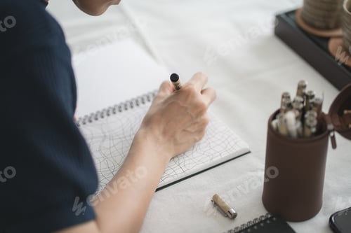 Preview: Top of hand drawing down on her notebook , work space concept.